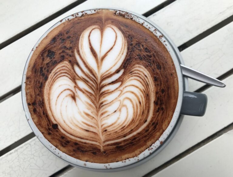 Top-down view of intricate latte art in a ceramic cup on a rustic table, perfect for coffee enthusiasts.